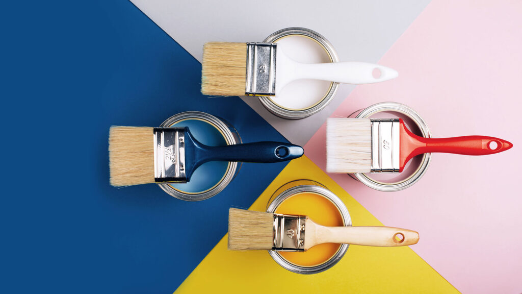 White, pink, yellow and blue paint pots with paint brushes