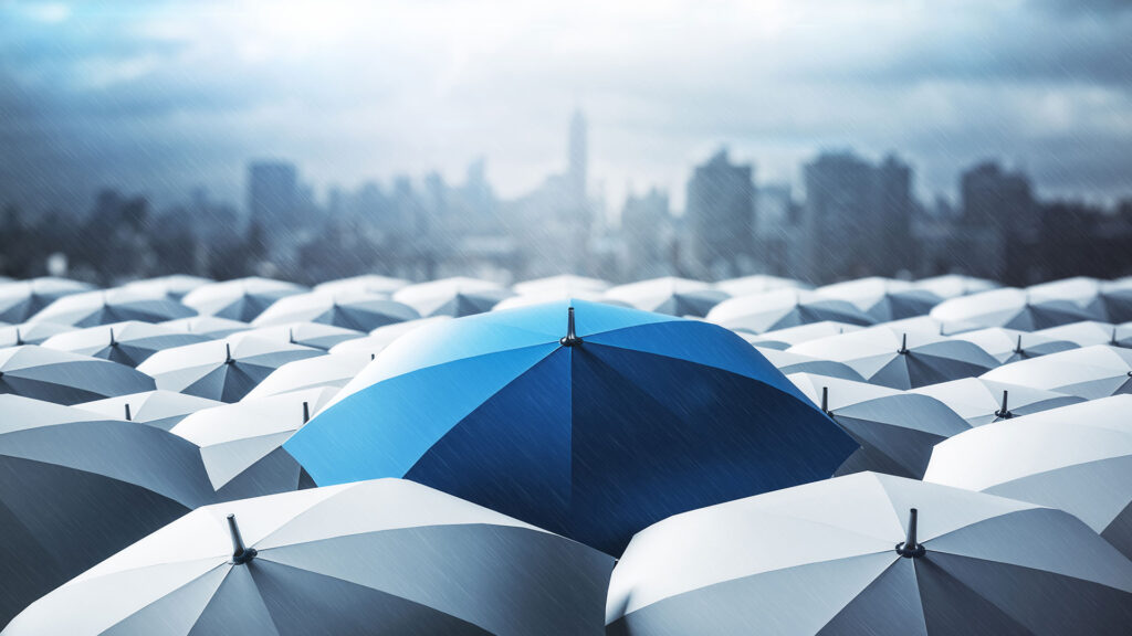 Blue umbrella in a crowd of grey umbrellas