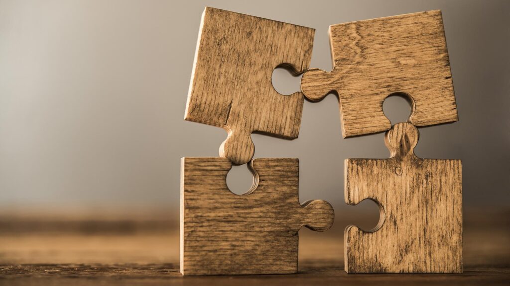 Four wooden pieces of puzzle almost coming together