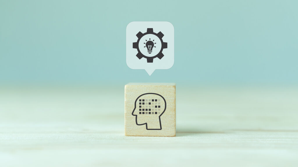 Cube with AI head on it and a cog with a lightbulb in it above