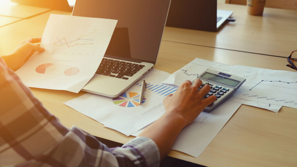 Business person using calculator and analysing charts