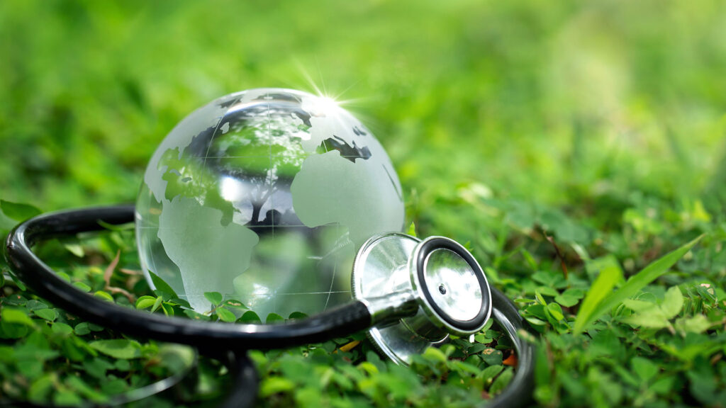 Doctors stethoscope wrapped around glass globe in the grass