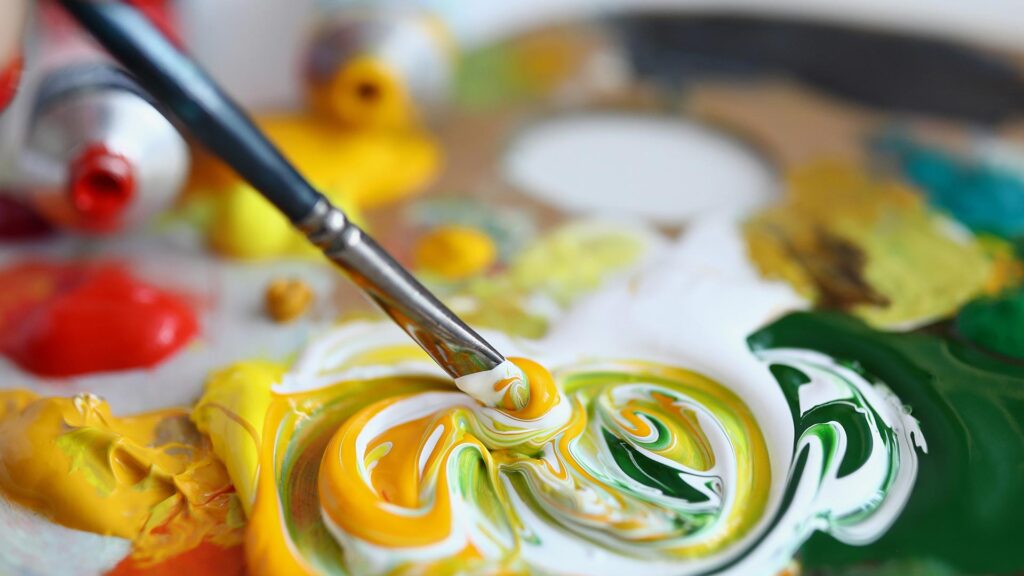 Person using paint brush to mix paint together