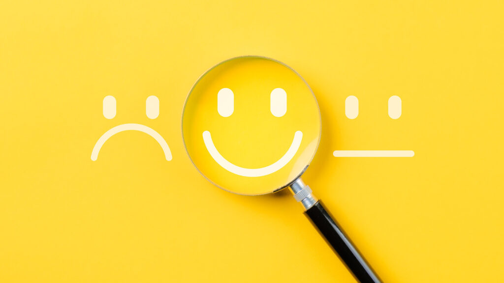 Magnifying glass focusing on happy face out of sad, happy and neutral